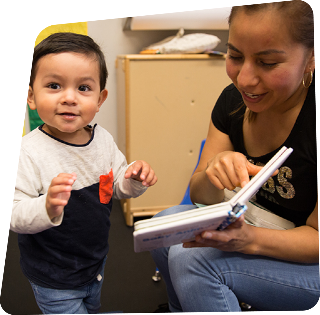 Educator reading a book to a toddler aged boy
