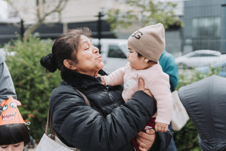 woman smiling and holding infant outside