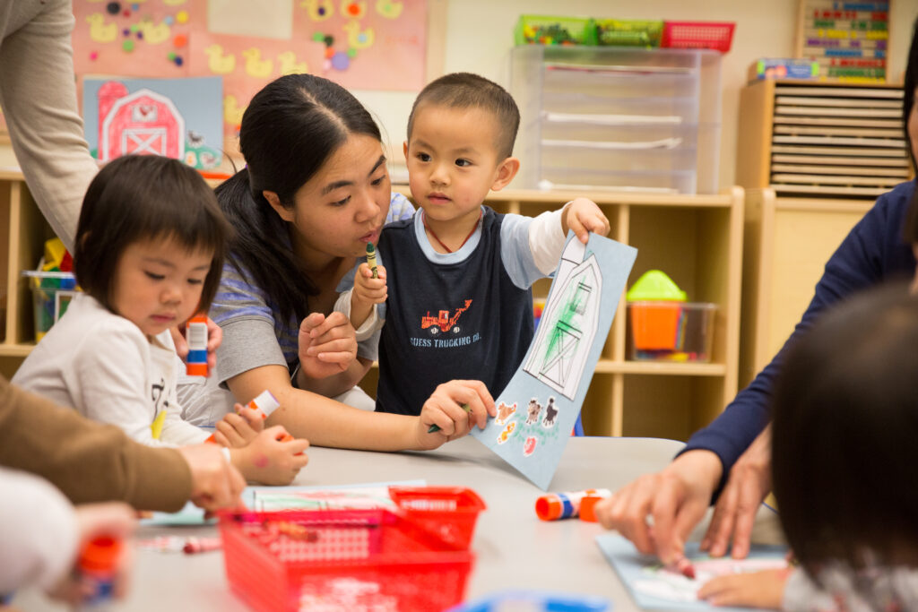 Young child at classroom table with teacher