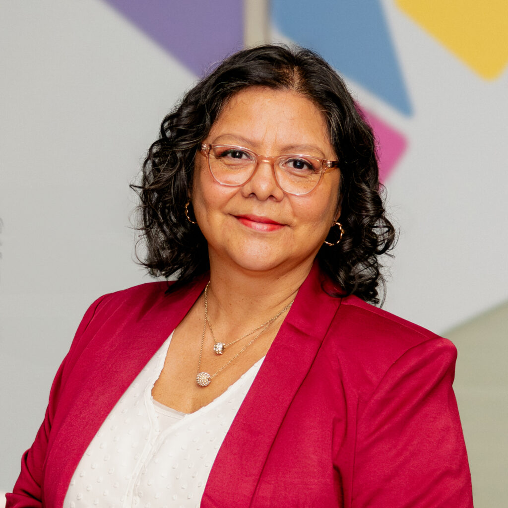 A headshot of our organization's executive director, with glasses and a red blazer.