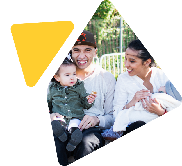 Happy family with two young children sitting on park bench