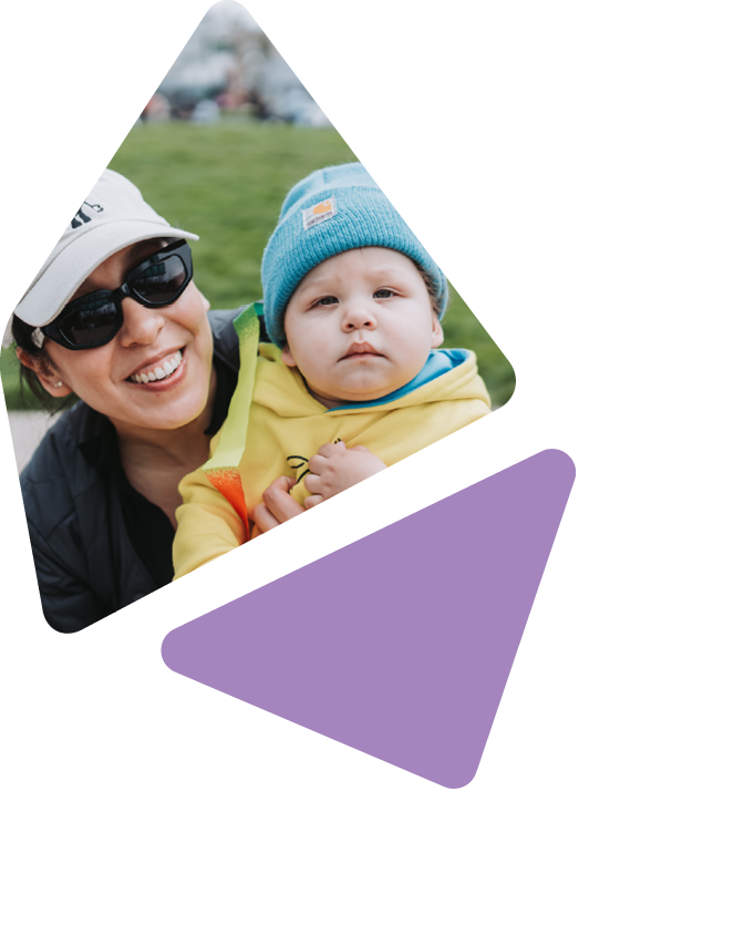 mother holding infant child outside, smiling at camera