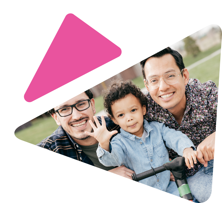 two fathers with their young son between them on a scooter, smiling at camera