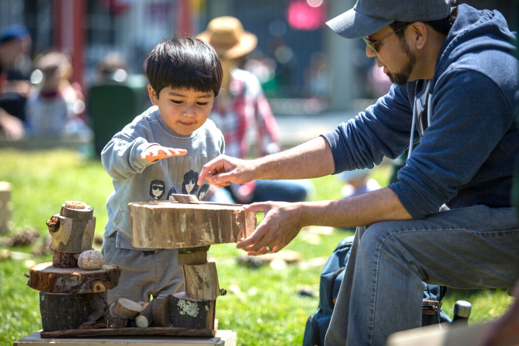 man and young boy outdoors looking at cross sections of tree trunks